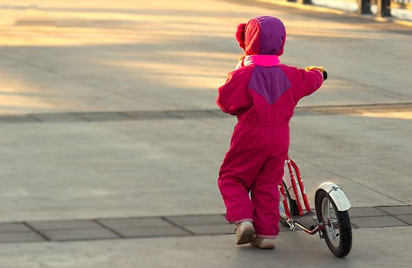 Flicka leder en sparkcykel.