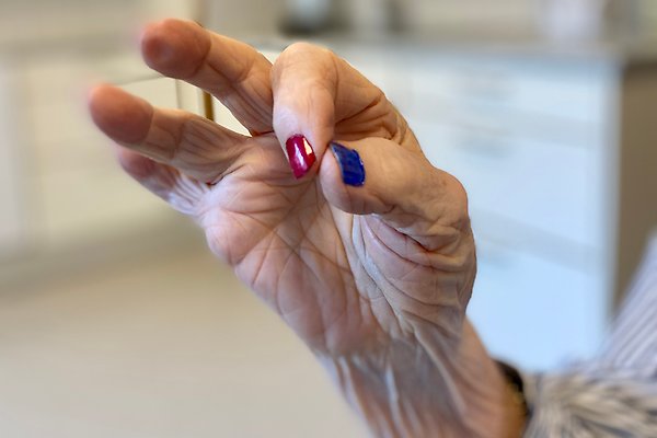 En äldre dams hand. Rött och blått nagellack.