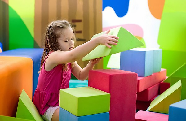 Flicka leker med stora, färgglada byggklossar.